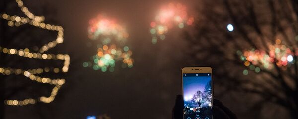 Женщина снимает на телефон Новогодний салют - Sputnik Latvija