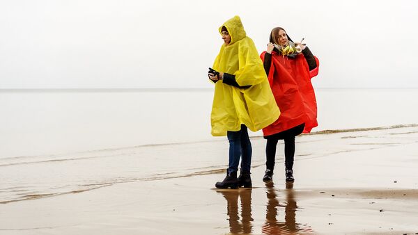 Девушки в дождевиках на пляже Юрмалы - Sputnik Латвия