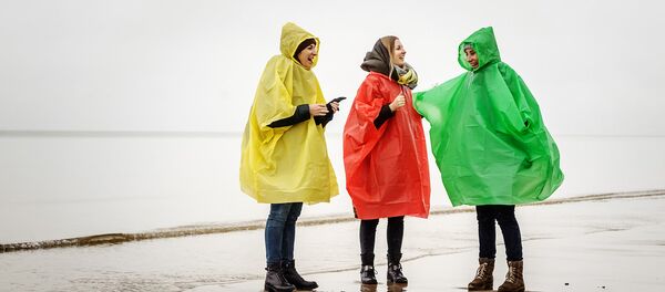 Девушки в дождевиках на пляже Юрмалы - Sputnik Латвия