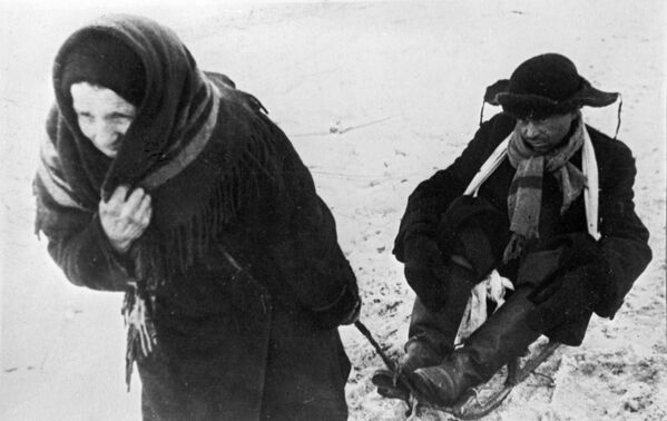 Женщина везет ослабевшего от голода мужа в дни блокады Ленинграда - Sputnik Латвия
