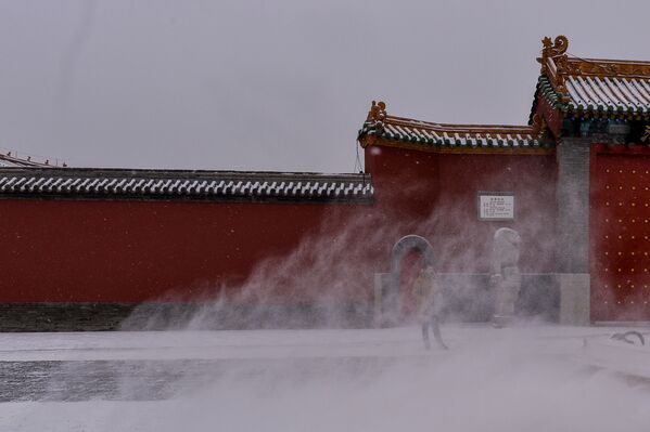 Китайский турист стоит у Императорского дворца во время снегопада в Шэньяне - Sputnik Латвия