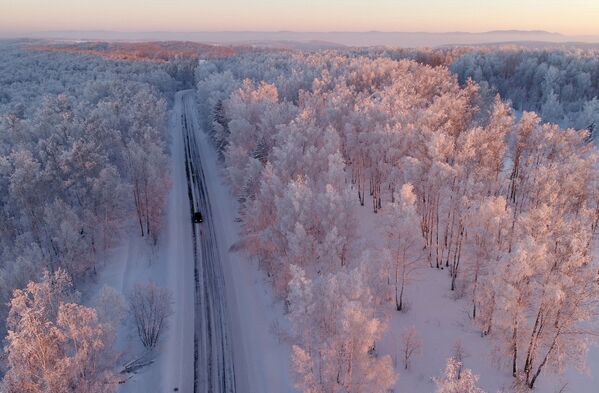 Машина едет по трассе вдоль заснеженного леса на закате, Красноярский край - Sputnik Латвия