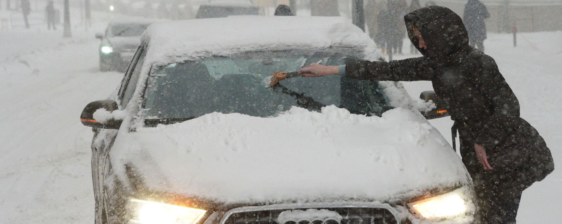 Владелица отчищает свою машину от налипшего снега во время снегопада в Москве - Sputnik Латвия, 1920, 09.12.2022