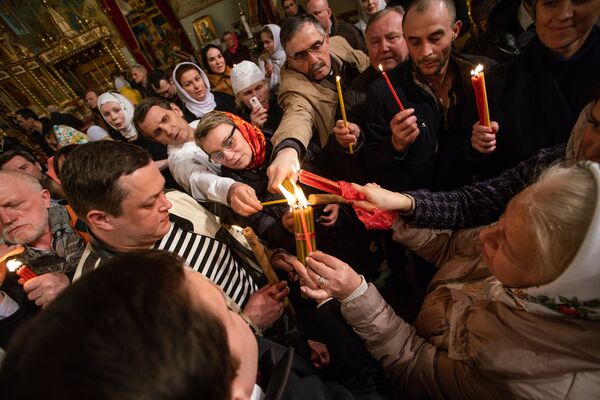 Православные христиане делятся Благодатным огнем, привезенным из Иерусалима - Sputnik Латвия