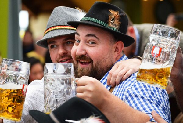 Apmeklētāji ar alus glazēm tradicionālā alus festivāla Oktoberfest atklāšanas pasākumā Minhenē - Sputnik Latvija